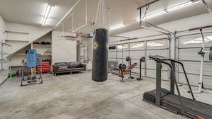 Tilava autotalli, jossa on nyrkkeilysäkki, painonnostopenkki ja juoksumatto.
