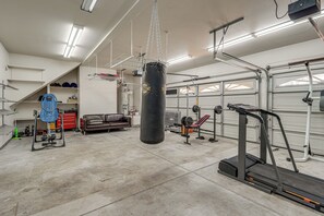 Eine geräumige Garage mit einem Boxsack, einer Gewichtbank und einem Laufband.