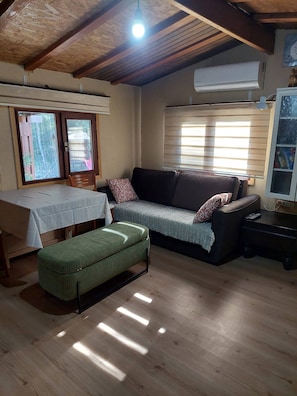 A cozy living room with a sofa, ottoman, and a table with a tablecloth. - Escape the noise, hear only nature’s voice (Karacahisar)