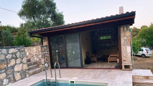 A stone-walled pool with a metal ladder, a stone building with a tiled roof, and a car parked outside. - Escape the noise, hear only nature’s voice (Karacahisar)