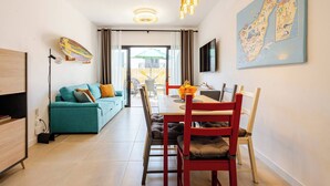 Una sala de estar moderna con un sofá, una mesa de comedor, sillas y un televisor montado en la pared.