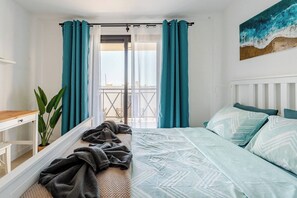 Une chambre à coucher avec un lit, une fenêtre avec des rideaux, une plante et une vue sur l’extérieur.