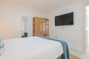 A bedroom with a bed, a television mounted on the wall, and a wooden wardrobe. - 2-Bedroom Apartment in Guargacho, Tenerife (Guargacho)