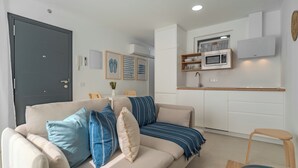 Una sala moderna con un sofá, una mesa de comedor y una zona de cocina con microondas y armarios.