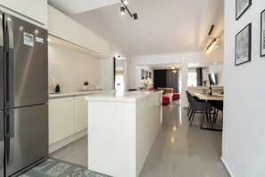 A modern kitchen with a central island, stainless steel appliances, and a dining area with a table and chairs. - Costa Adeje 3BR Villa, Pool, BBQ, AC, Sleeps 8 (Costa Adeje)