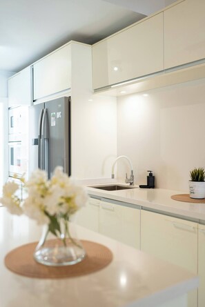 A modern kitchen with a stainless steel refrigerator, a sink with a faucet, and a vase with flowers on the counter. - Costa Adeje 3BR Villa, Pool, BBQ, AC, Sleeps 8 (Costa Adeje)