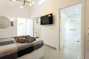 A modern bedroom with a bed, a flat-screen TV, a mirror, and a walk-in closet. - Costa Adeje 3BR Villa, Pool, BBQ, AC, Sleeps 8 (Costa Adeje)