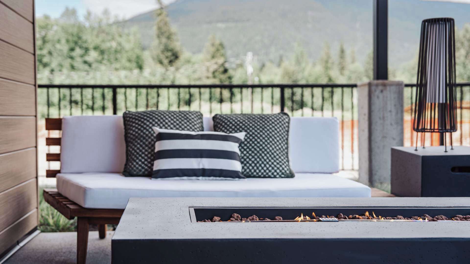 A balcony with a sofa, pillows, a fire feature, and a view of mountains.