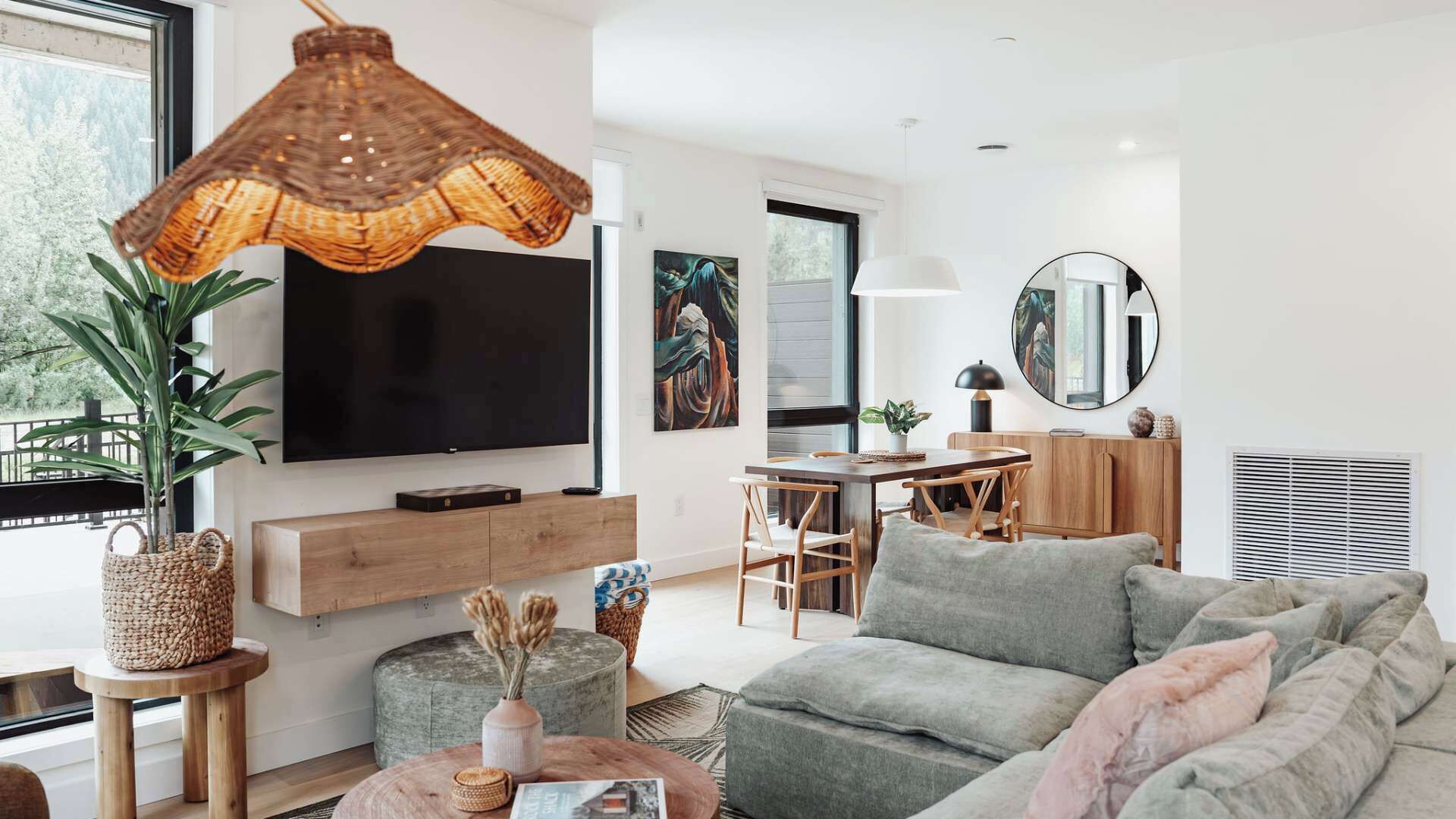 A modern living room with a flat-screen TV, a dining area, and a large window.
