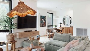 Ein modernes Wohnzimmer mit einem Flachbildfernseher, einem Essbereich und einem großen Fenster.