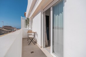 A balcony with a table and chairs, a sliding glass door, and a view of the cityscape. - 2-Bedroom Apartment in Guargacho, Tenerife sur (Guargacho)