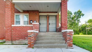 A brick building with a porch, a double door, and a set of concrete steps leading to the entrance. - Family-Friendly Detroit Duplex: Walk to Parks! (Detroit)