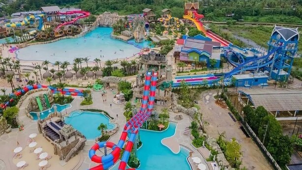 Parque acuático con varias toboganes y piscinas, rodeado de vegetación.