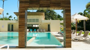 A pool area with lounge chairs and a covered seating area. - El mar te llama · 2BR Los Corales (Punta Cana City)