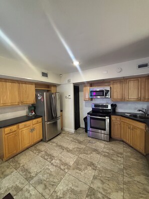 A kitchen with wooden cabinets, stainless steel appliances, and a tiled floor.