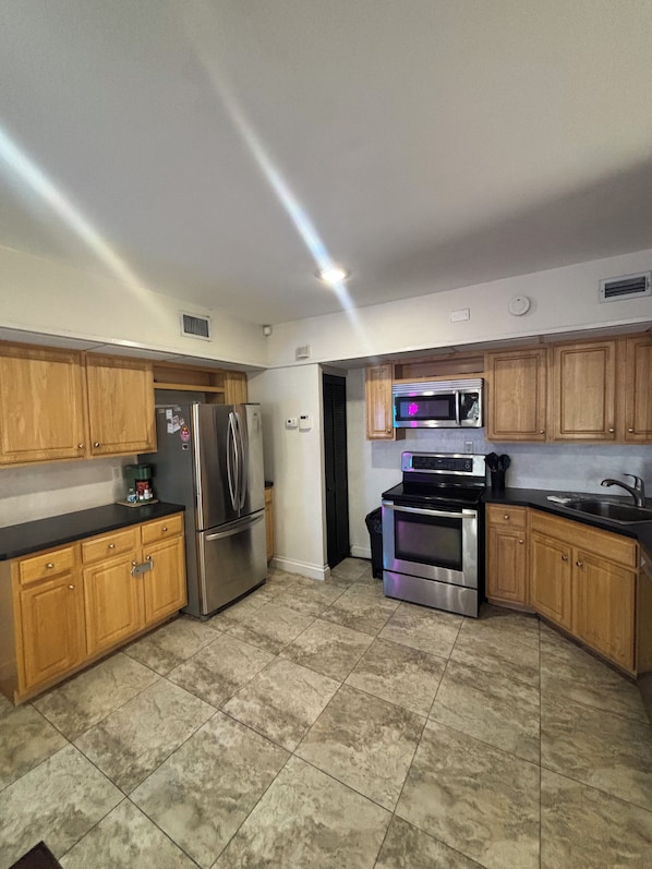 A kitchen with wooden cabinets, stainless steel appliances, and a tiled floor.