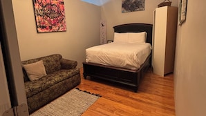 A bedroom with a bed, a sofa, a rug, a ceiling light fixture, and artwork on the walls. - THE ONLY HOUSE IN CHANNELSIDE BY WATER STREET (Tampa)