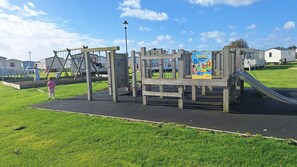 Ein Spielplatz mit Schaukeln, einer Rutsche und einer Kletterkonstruktion.
