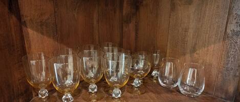 A wooden shelf with multiple clear glass goblets.