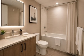 A bathroom with a sink, toilet, and bathtub. - Norvian Urban Suites (Toronto)
