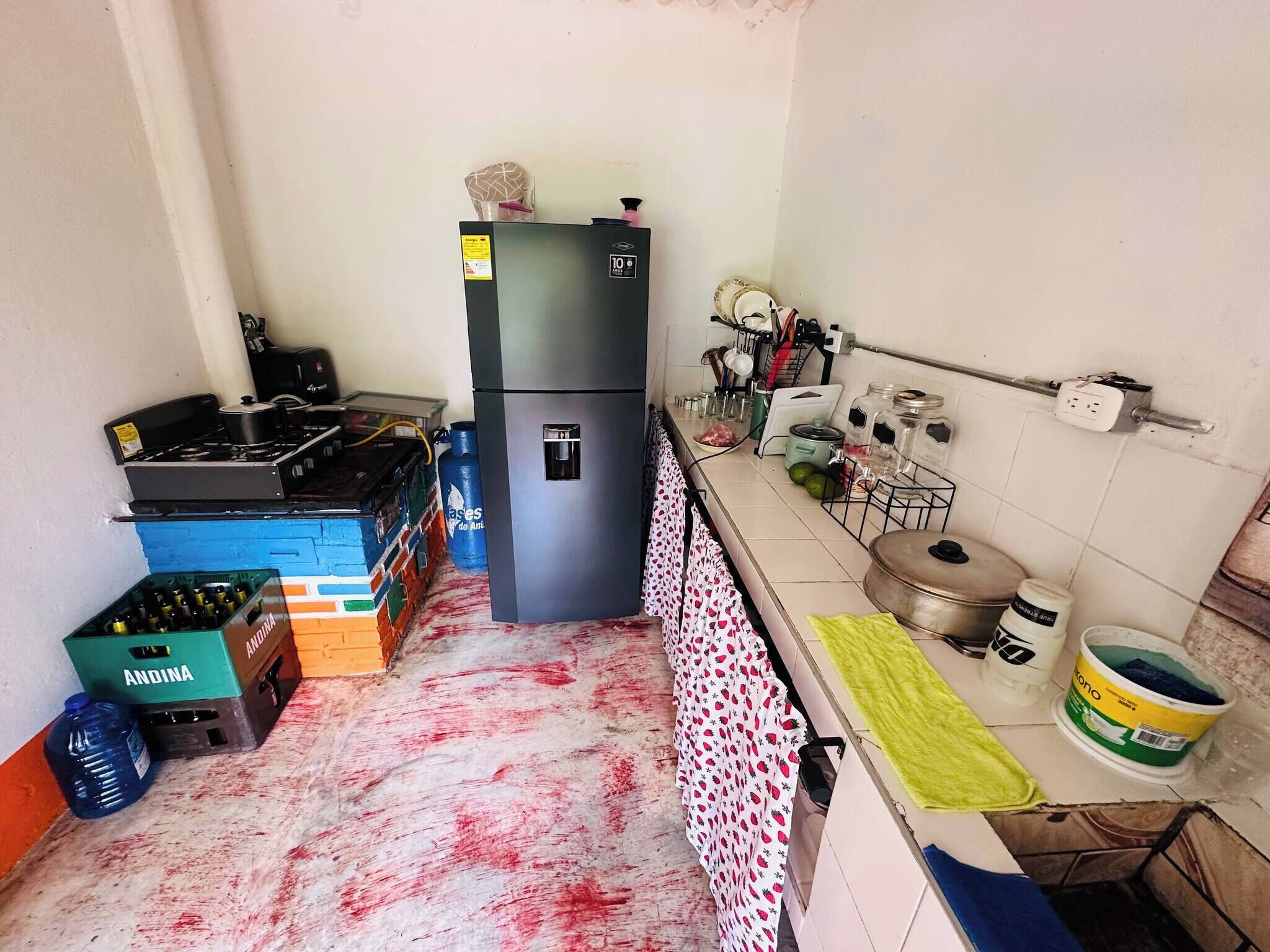 A compact kitchen with a refrigerator, gas stove, and various kitchen utensils.