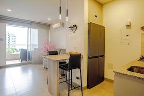 A modern kitchen with a built-in refrigerator, a bar counter, and a dining area with a chair. - Modern Beachfront Loft in Santa Marta (Urb Don Jaca)