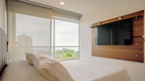A hotel room with a bed, a large window, and a mounted television. - Apartament with view at the sea close at the airport (Urb Don Jaca)