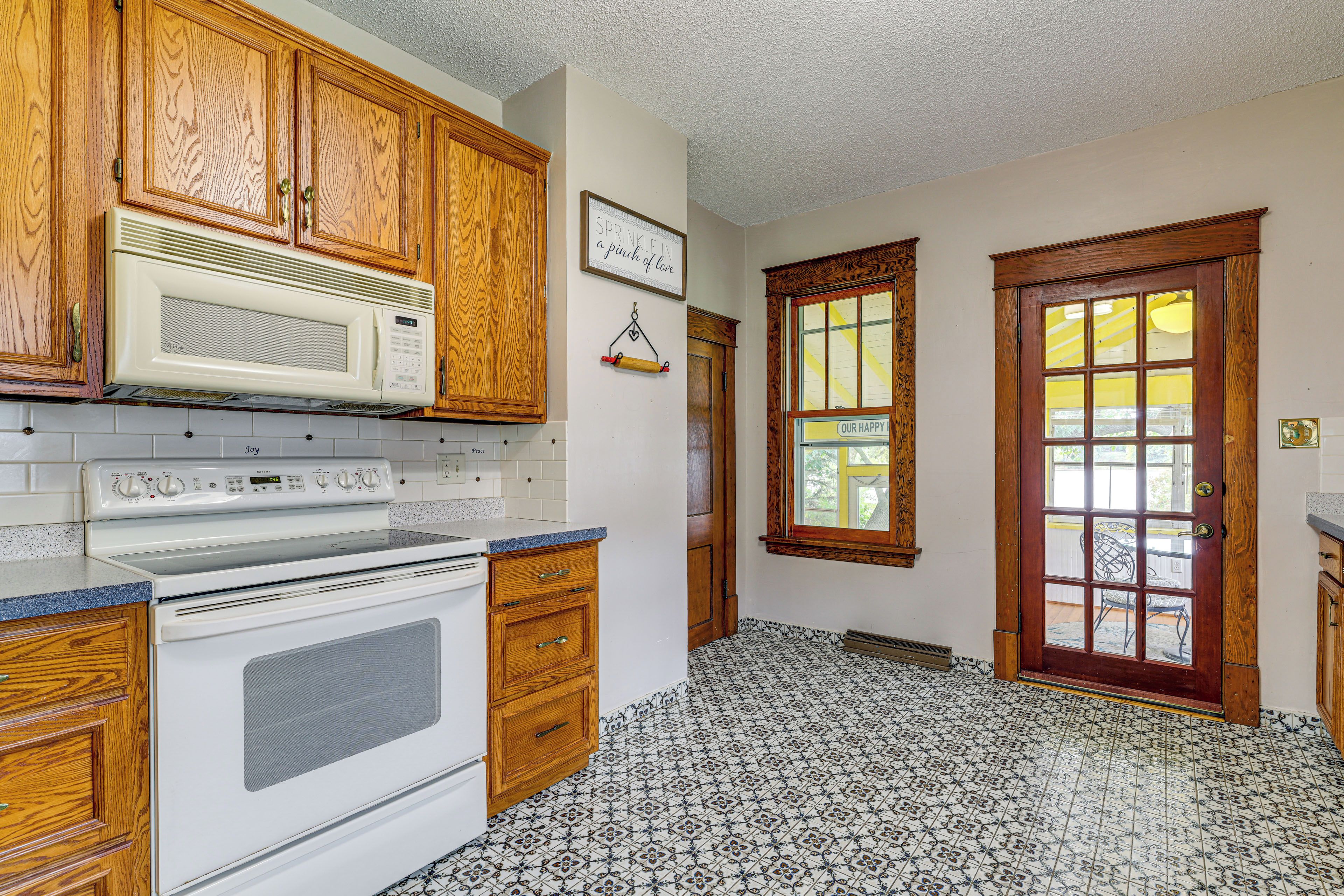 Une cuisine avec des meubles en bois, un four à micro-ondes, un four traditionnel et un sol carrelé à motifs.