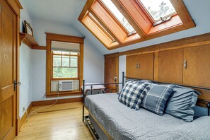 Un dormitorio con tragaluz, armario de madera y cama con colcha.
