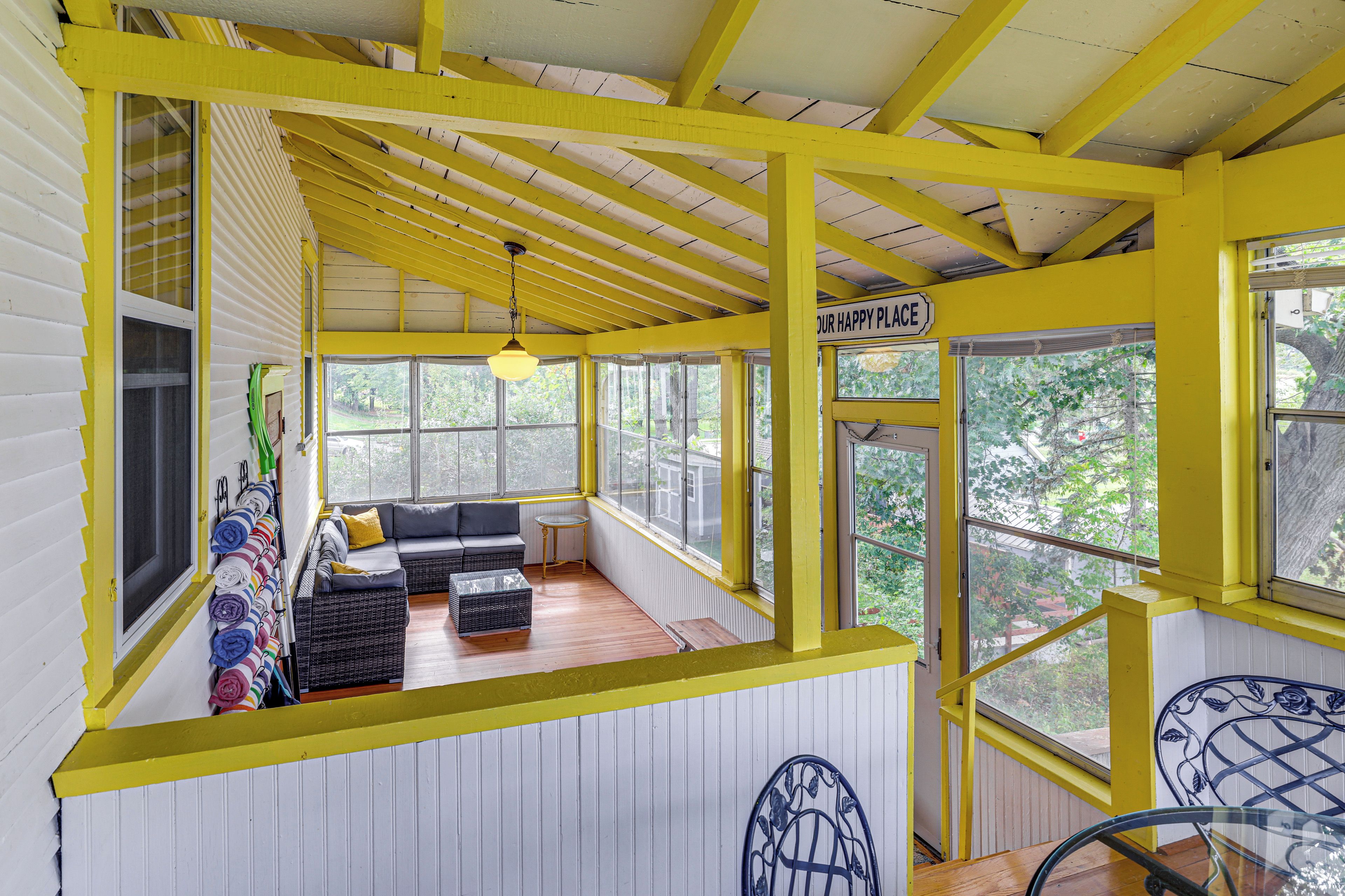 Una habitación con una decoración en tonos amarillo y blanco, que incluye un sofá, una mesita y una lámpara colgante.