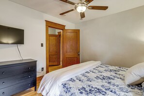 A bedroom with a bed, dresser, ceiling fan, and a TV mounted on the wall. - Historic Home on Beaver Dam Lake w/ Seasonal Dock (Cumberland)
