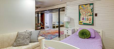 Une chambre à coucher comprenant un lit, un canapé, une table de chevet et un jeu de société fixé au mur.