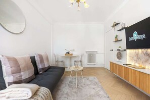 Ein modernes Wohnzimmer mit einer Couch, einem kleinen runden Tisch und einer Rezeption mit einem Logo.