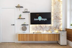 Ein Empfangsbereich mit an der Wand montiertem Fernseher, der das AeroStays-Logo zeigt, einem Holzbüro und einer Marmorwand.
