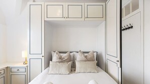 A bedroom with a bed, pillows, a nightstand, a lamp, and a wardrobe. - St John's Wood Flat with Spa Bath (Greater London)