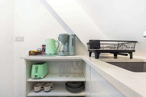 Eine Küche mit Kaffeemaschine, Toaster und einem schwarzen Geschirrgestell.