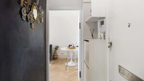 A doorway leading to a room with a white door, a mirror with floral decorations, a small table with a vase, and a white cabinet. - St John's Wood Flat with Spa Bath (Greater London)