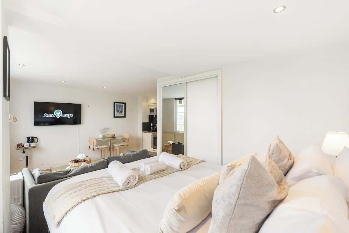 A hotel room with a bed, a TV, a desk, and a mirror.