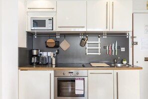 Eine Küche mit Mikrowelle, Kaffeemaschine, Toaster, Backofen und hängendem Kochgeschirr.