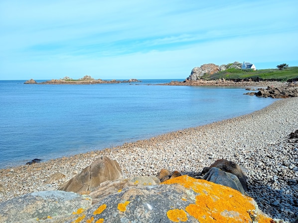 A pebbled beach with a rocky outcrop and a house in the background. - A small, cozy cottage with a fireplace and an enclosed garden in the Monts d'Arrée, 30 minutes from the sea (Scrignac)