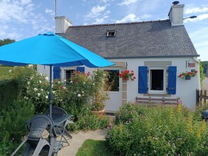 A house with a blue awning, a small window, and a door. - A small, cozy cottage with a fireplace and an enclosed garden in the Monts d'Arrée, 30 minutes from the sea (Scrignac)