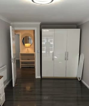 Ein Flur mit einem weißen Kleiderschrank, einem Holzschrank und einem Spiegel.