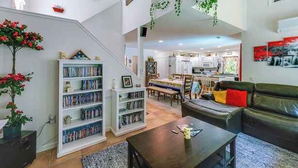 Un amplio salón con una escalera, una estantería, un comedor y una cocina.