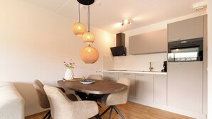 Una cocina moderna con una mesa redonda de comedor, sillas e iluminación colgante.