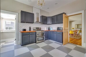 A modern kitchen with dark cabinets, a tiled backsplash, and a checkered floor. - Walk to Parks & Dining! Historic Eustis Home (Eustis)