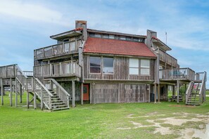A wooden multi-story building with balconies, a red-tiled roof, and a grassy yard. - Walk to Matagorda Beach! Condo w/ Pool Access (Matagorda)