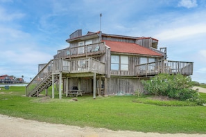 A wooden house with a red roof, a balcony, and a staircase leading to the upper level.