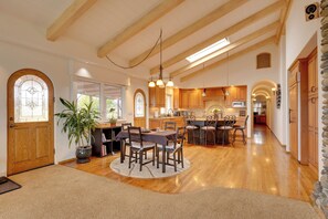 A spacious kitchen with wooden beams, a dining area with a round table, and a stone wall. - Ocean View + Private Garden: Santa Cruz Home (Santa Cruz)