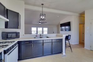Eine moderne Küche mit dunklen Schränken, einer Mikrowelle, einem Herd und einem Deckenventilator.