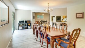 Uma área de refeições com uma grande mesa de madeira, cadeiras e um candelabro.